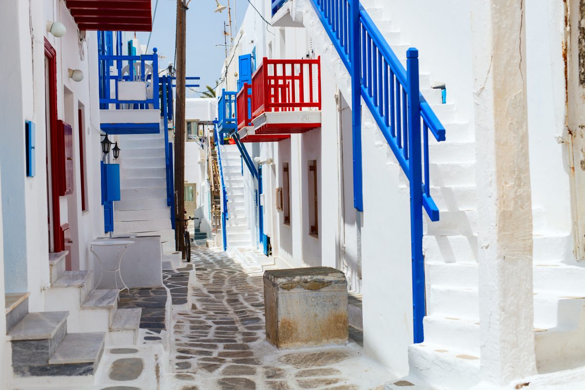 Typical street of greek traditional village with white walls and colorful doors, windows and balconies on Mykonos Island, Greece, Europe