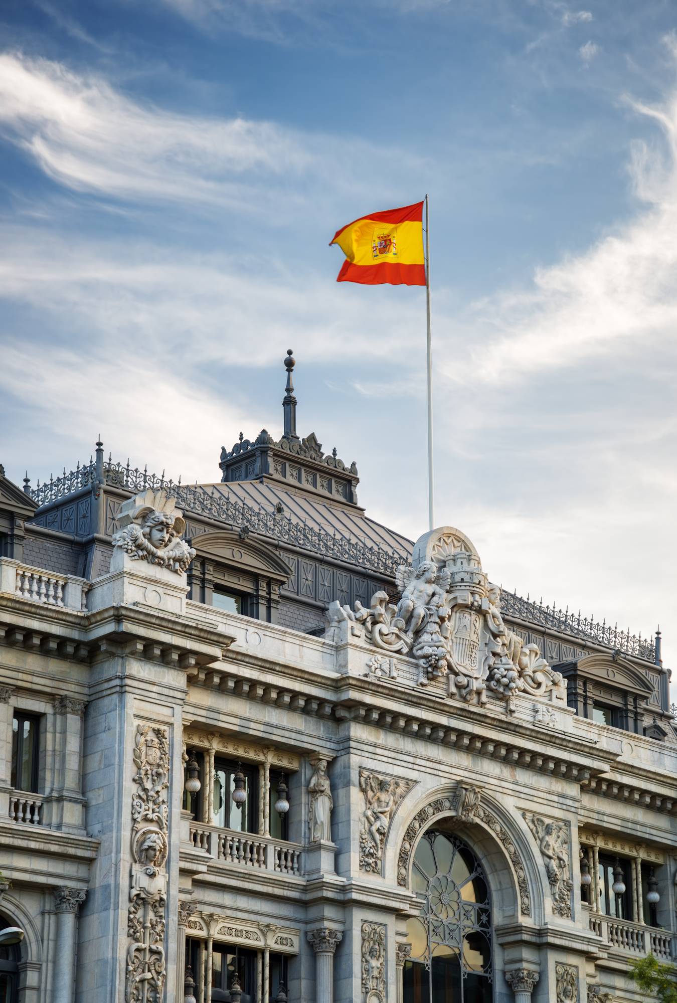 The flag of Spain fluttering on building of the Bank of Spain (Banco de Espana) in Madrid, Spain. Madrid is a popular tourist destination of Europe.